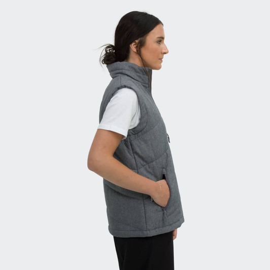 A woman in profile wearing a grey puffer vest with a hood and side pockets. The vest has a logo.