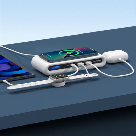 A white wireless charging station with a phone, smartwatch, and earbuds connected by cables, placed on a blue surface.