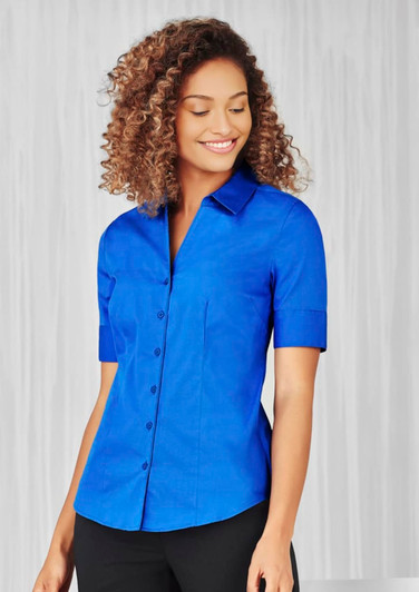 A blue short sleeve button-up shirt for women with a fitted design and a collar, featuring a logo.