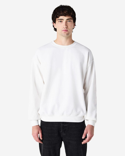 A white crewneck sweatshirt with long sleeves, featuring a relaxed fit and a simple design. It has a logo.