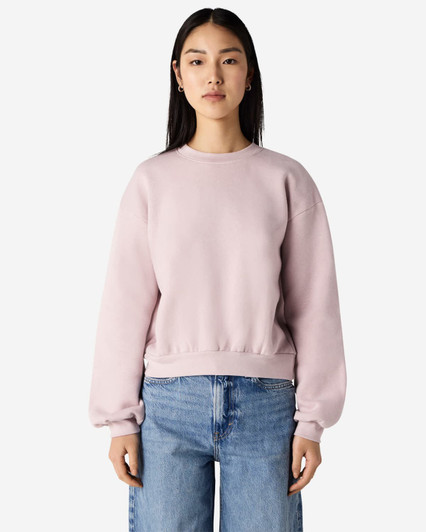 A women's crewneck sweatshirt in a soft pink colour, featuring a relaxed fit and long sleeves. It has a logo.
