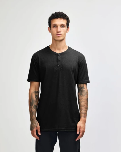 A black unisex Henley T-shirt featuring a button placket and short sleeves, modelled by a person.