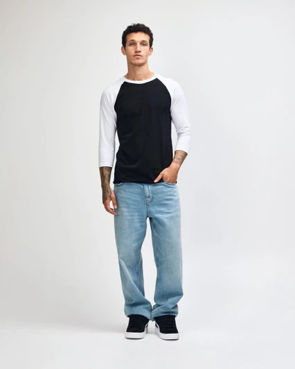 A unisex raglan T-shirt with a black body and white three-quarter sleeves, paired with light blue jeans and black sneakers.