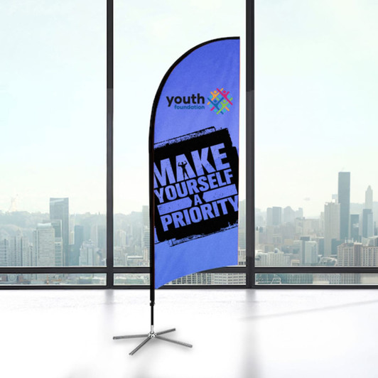 A small feather flag kit featuring a blue background and a logo, displayed indoors with a city skyline view.