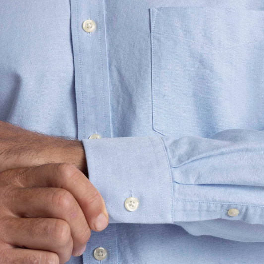Light blue button-up shirt with a chest pocket and cuff detailing, featuring a logo on the chest.