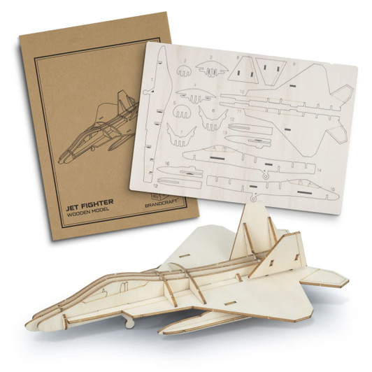 A wooden model of a jet fighter in light wood tones, alongside a die-cut sheet and packaging with a logo.