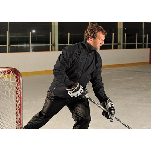 A man wearing a black Men's Axis Thermal Jacket on an ice rink, holding a hockey stick. The jacket has a logo.