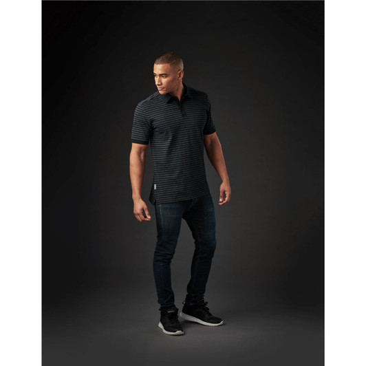 A men's polo shirt in black with striped detailing, paired with dark jeans and sneakers. The shirt features a logo.