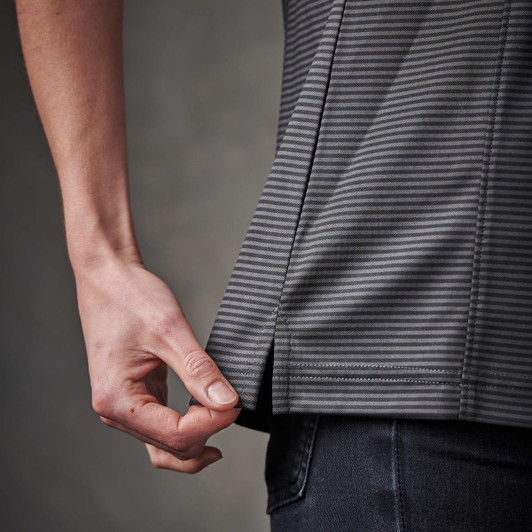 A close-up of a grey striped women's polo shirt, featuring a stylish split at the hem, being adjusted by a hand.