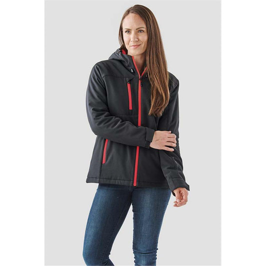 A woman wearing a black insulated softshell jacket with red accents and a hood, standing against a neutral background.