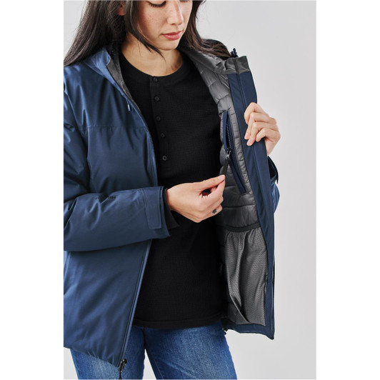 A woman wearing a navy lightweight shell jacket, showing the inside pocket. The jacket features a branding logo.