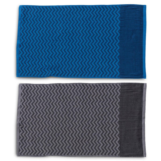 Two gym towels displayed, one in blue with a patterned design and the other in grey with a similar pattern, both featuring a pocket.