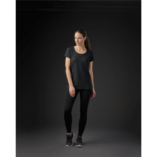 A women's crew neck tee in black with subtle stripes, paired with black leggings and sports shoes. The tee features a logo.