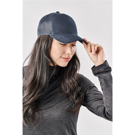 A navy Scirroco Trucker cap with mesh sides, worn by a woman touching the peak.
