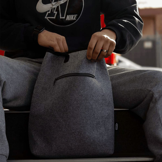 A grey recycled felt cooler tote bag with a zipper pocket, being held by a person wearing casual attire.