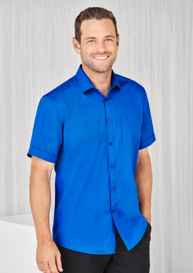 A blue short sleeve shirt with a button-up front and a chest pocket, featuring a logo on the fabric.