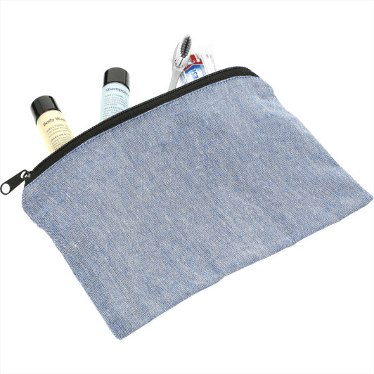 A blue recycled cotton twill pouch containing travel-sized toiletries and a toothbrush, featuring a zip closure.