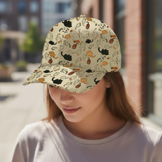 A custom cap featuring a beige background with colourful cat illustrations, worn by a person outdoors.
