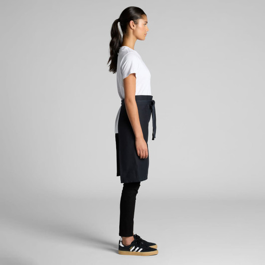 A half apron in dark grey, featuring a waist tie, paired with a white T-shirt and black pants.