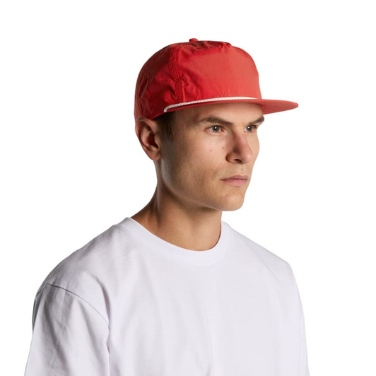 A red cap with a flat brim, featuring a logo, worn by a man in a white t-shirt.