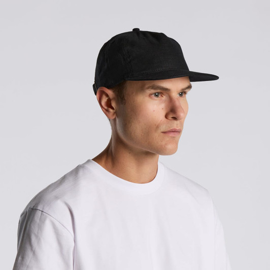 A black cap with a flat brim, featuring a logo, worn by a person in a white T-shirt.