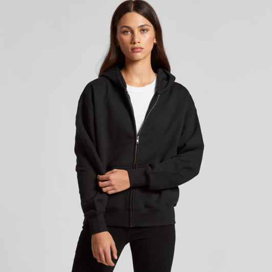 A black zip-up hoodie with a hood, featuring a front zip and long sleeves. The model poses casually.