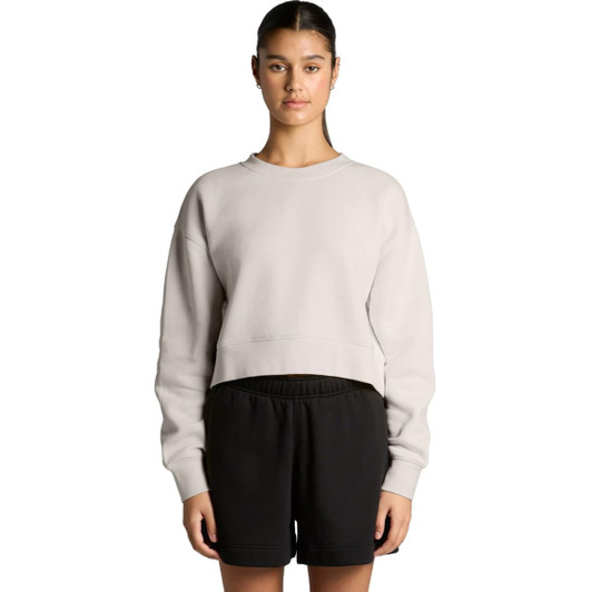 A cropped, light grey jumper with a relaxed fit, paired with black shorts. The model stands with arms by her side.