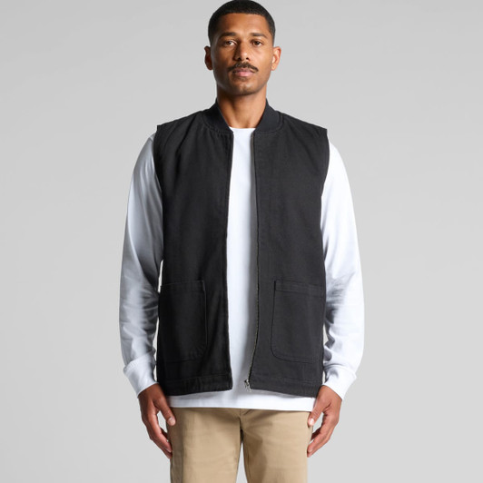 A black canvas heavy vest with two front pockets, worn over a white long-sleeve shirt.