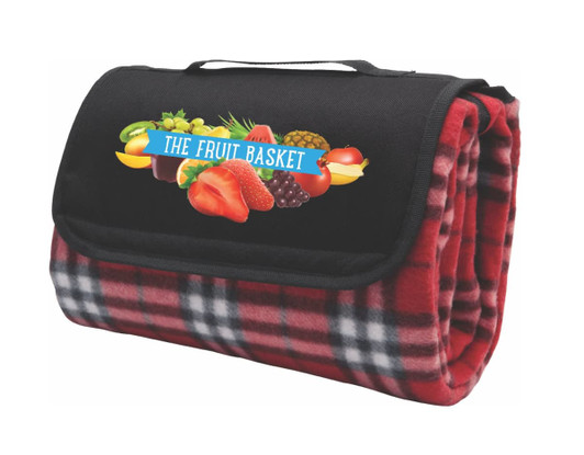 A folded red check picnic rug featuring a black canvas flap with a logo, showcasing a fruit graphic.