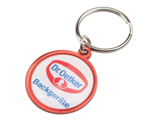 A round keyring featuring a red border and a central design with text. The keyring includes a metal keychain attachment.