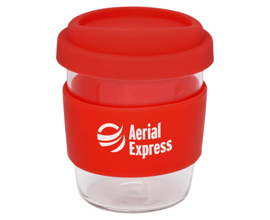 A reusable coffee cup with a transparent body, red silicone lid, and a red silicone band. It features a logo.