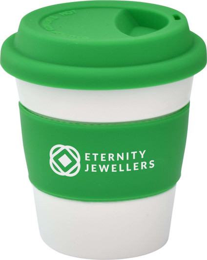 A reusable coffee cup featuring a green silicone lid and sleeve with a white body. The cup has a logo.