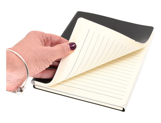 A hand holding the black and white "Two to Tango" A5 notebook, revealing lined pages inside.