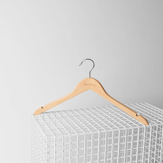 A wooden hanger with a silver hook, featuring a logo, resting on a white wire grid.