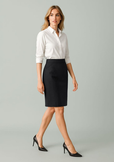 A woman wears a black pencil skirt paired with a white shirt and black heels, showcasing a sleek, professional look.