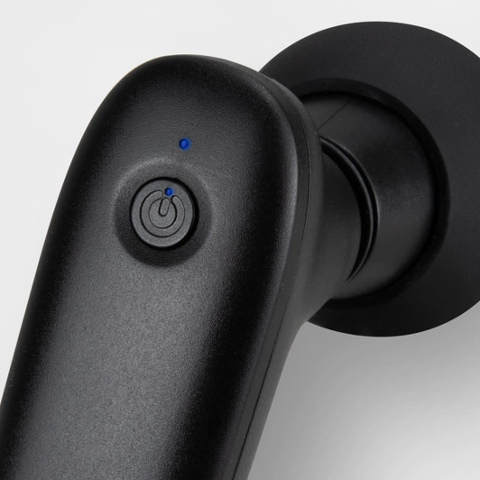 A compact handheld massager in black with a power button and a blue indicator light.