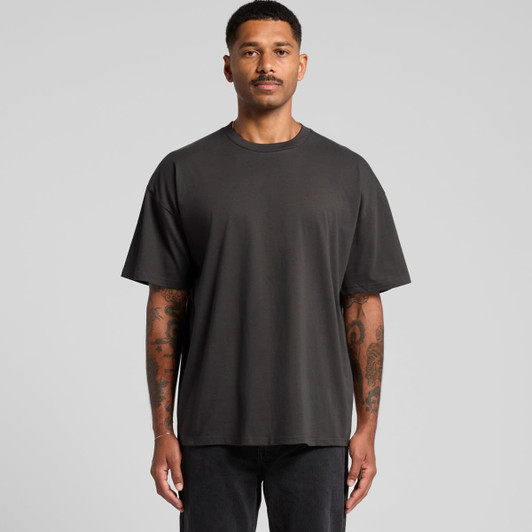 An oversized black t-shirt on a model with tattoos, featuring short sleeves and a relaxed fit. 