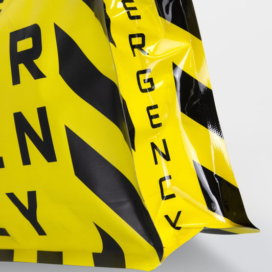 A large foil flat bottom pouch in bright yellow and black with a logo. It features a cautionary pattern.