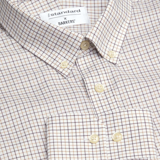 A button-up shirt with a check pattern in cream and brown tones, featuring a collar and buttons.
