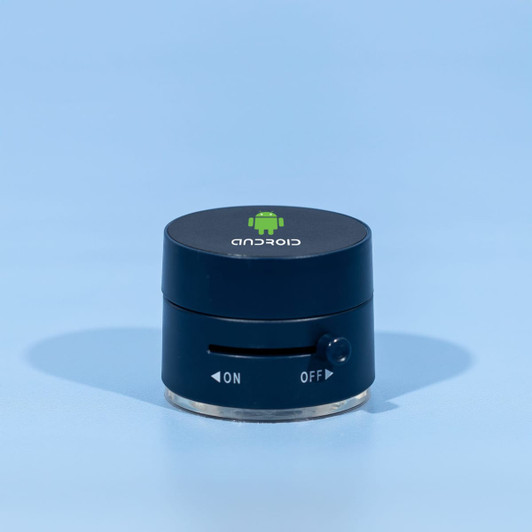 A black and silver device with a logo on top and a dial on the side, resting on a blue background.