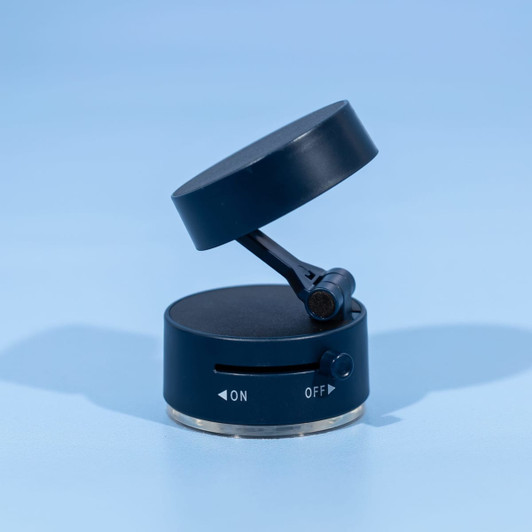 A black and silver vacuum suction phone stand with a rotating top and an on/off switch. It features a logo.
