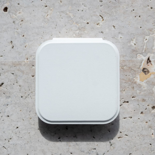 A white compact mirror with an LED light, featuring a square shape and a smooth surface, resting on a textured stone background.