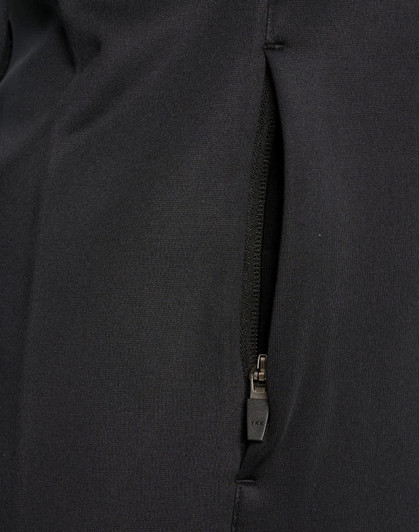 A close-up of a black softshell jacket featuring a zipped pocket. The fabric appears smooth and durable.