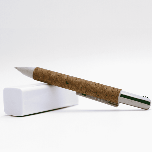 A cork pen with a metallic tip, resting on a white eraser. The pen has a natural brown cork casing.