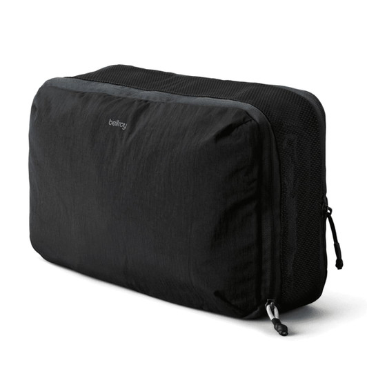A black packing cube with a mesh panel, featuring a logo and a zipper closure.