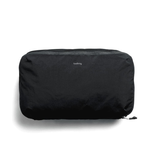 A black packing cube with a zipper and a small logo, designed for travel organisation.