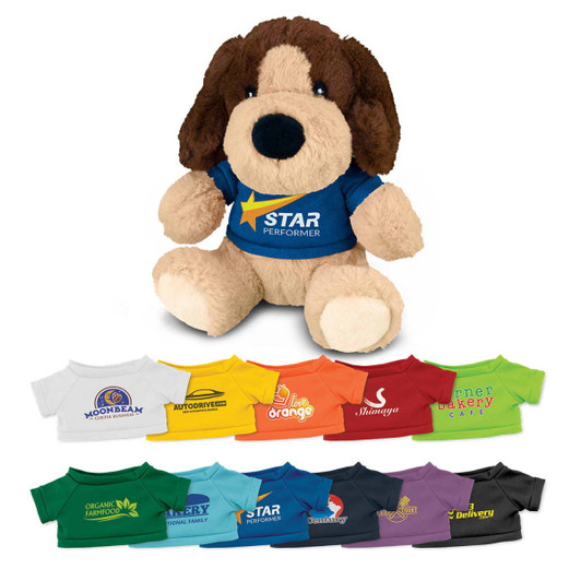 A stuffed dog plush toy with brown fur and a blue T-shirt featuring a logo. Various brightly coloured T-shirts are displayed below.