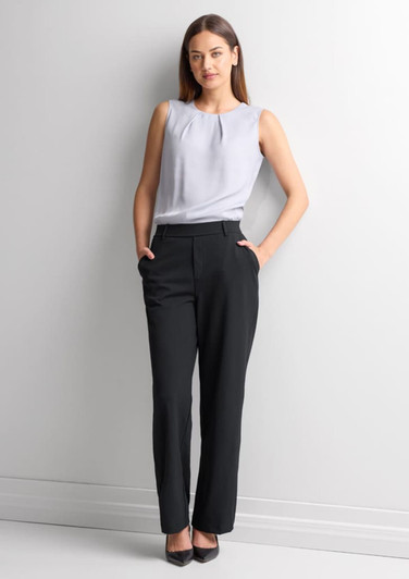 A woman wearing black soft stretch pants paired with a light grey top, standing against a plain background.
