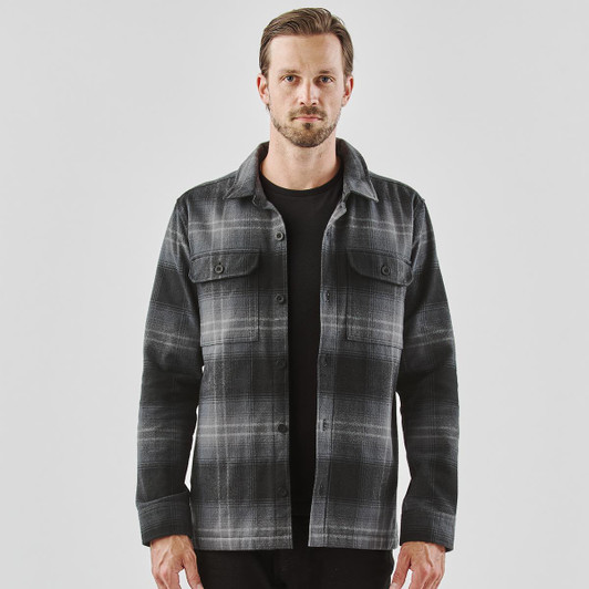 A men's shacket in black and grey Highland plaid, featuring a button front and two chest pockets.