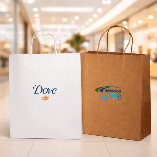 Two paper shopping bags are displayed, one white with a logo and the other brown with a logo, set in a retail environment.